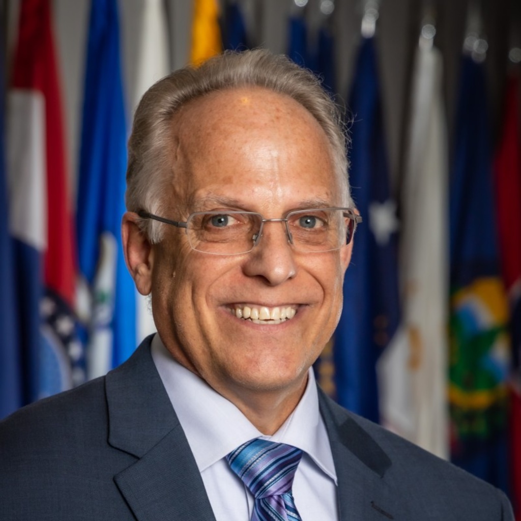 Man smiling at the camera. Background of flags