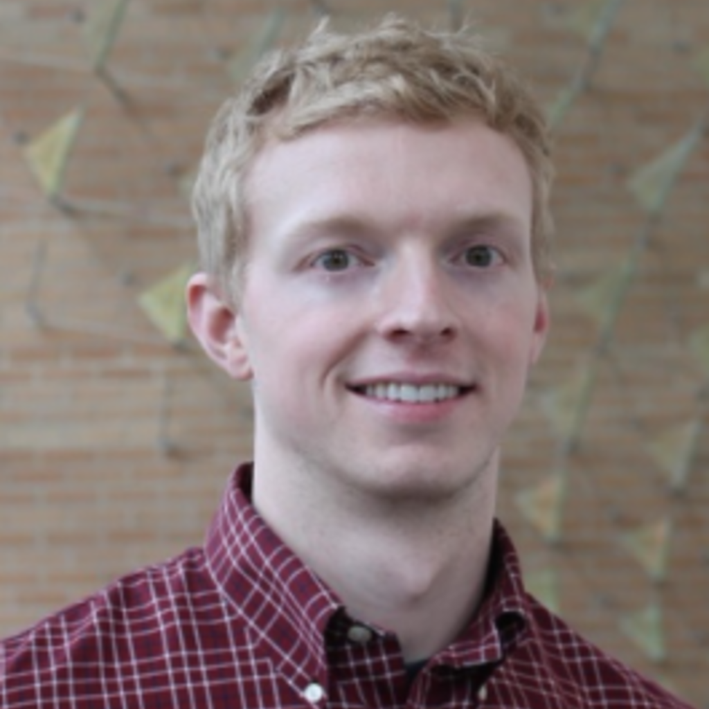 Man with short smiling at the camera. Tan background