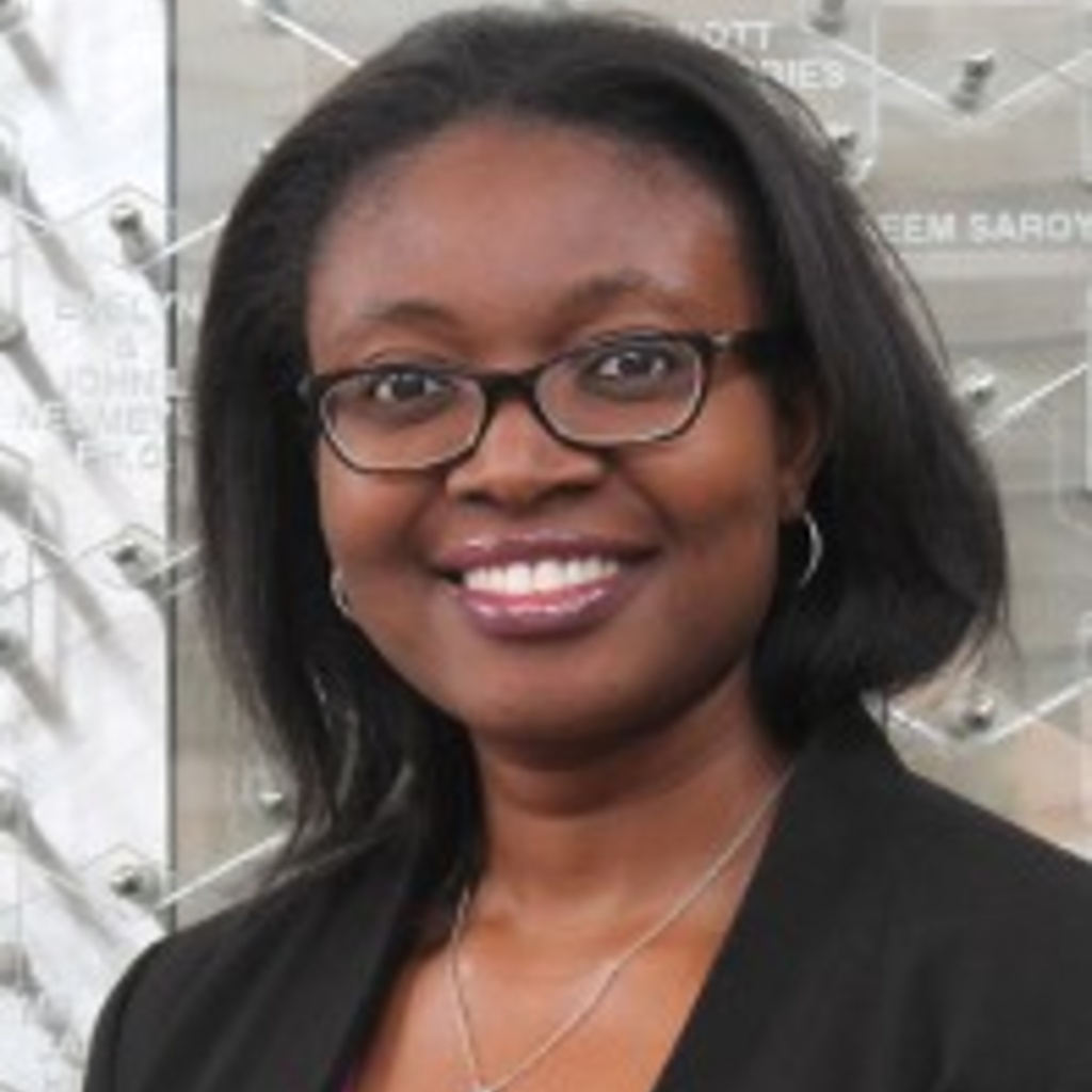 Woman with short black hair, smiling, wearing black glasses